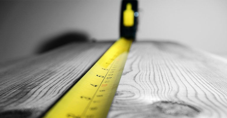 OffPageSEO_10 • Andrew Roche SEO A yellow tape measure is extended across a wooden surface, with the numbers clearly visible and the focus on the midsection. The image conveys precision, measurement, or the concept of assessing length or distance.